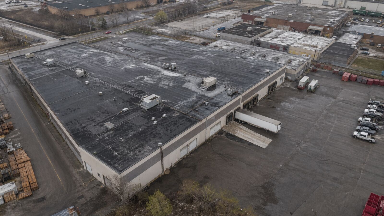 Flat commercial roof, HVAC units, and paved yard from above.